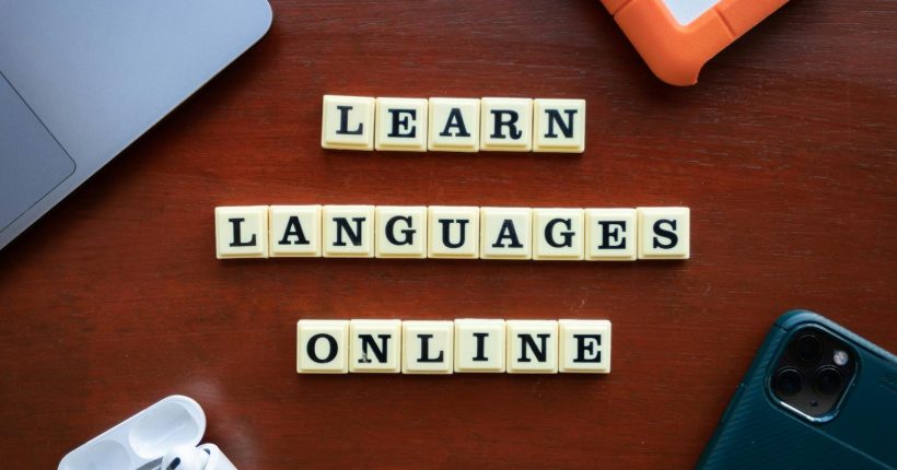 Photo by Ling App Flat lay of language learning tools with devices and text blocks on desk.