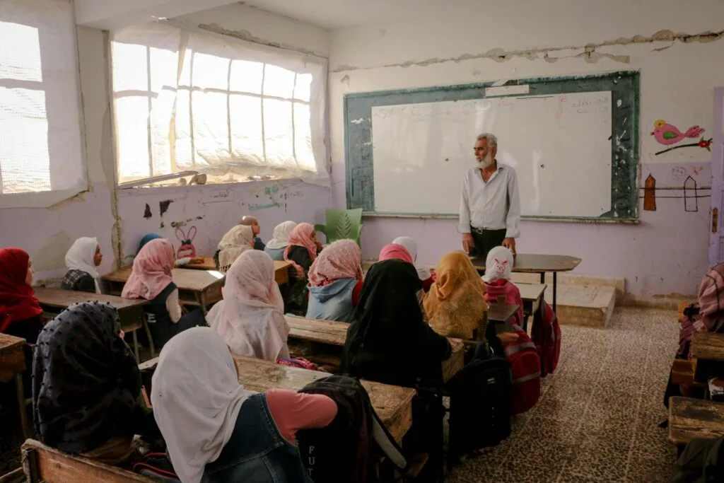 A classroom in Idlib, Syria, captures a teacher engaging students in a lively educational session.